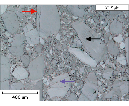 Une micrographie montre une structure granulaire avec des grains de différentes tailles et formes, certains étant indiqués par des flèches de couleurs variées, avec une échelle de 400 micromètres.
Description générée par IA